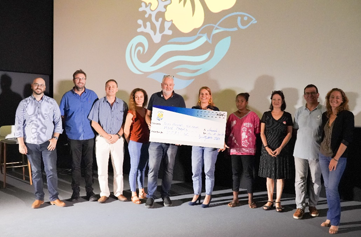 Remise des prix naturAction NC 2023 Group of ten adults standing on a stage, holding a large ceremonial check.